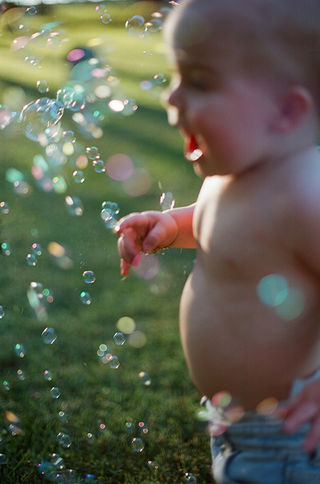 a baby walking through bubbles during a family photography session with charlottesville photographer Laura Richards