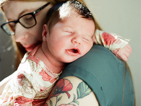 a newborn girl sleeps on her mother's shoulder