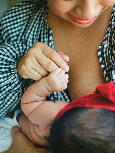 A baby grasps her mother's hand during an at-home newborn photography session in Charlottesville, Virginia