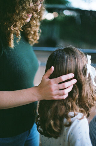 a mom placing her hand gently on her daughter's head during a family session with charlottesville family photographer Laura Richards