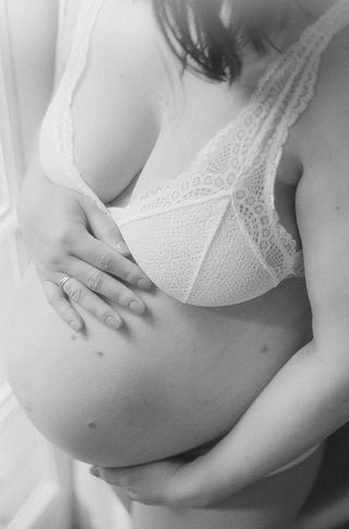 a close-up of a pregnant mother touching her belly during an intimate and relaxed at-home maternity session in charlottesville virginia