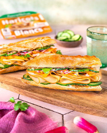 Sandwich baguette garni de crudités croquantes et protéines végétales, mise en scène colorée en lumière naturelle par photographe culinaire à Nantes