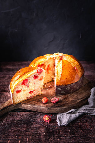 Brioche moelleuse aux pralines roses, coupe gourmande sur planche en bois, photographie culinaire en lumière douce.