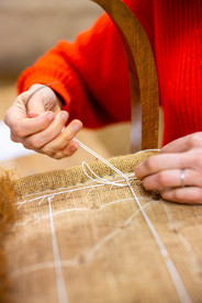 Gros plan sur la couture du crin lors de la restauration d’un fauteuil, geste précis effectué dans l’atelier tapissier Fauteuil de Famille à Cholet.