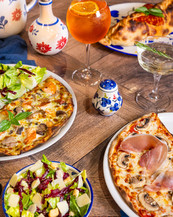 Sélection de pizzas italiennes Signorizza photographiées en ambiance chaleureuse avec cocktail et huile pimentée