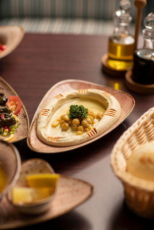 a plate of hummus with chickpeas and parsley on top
