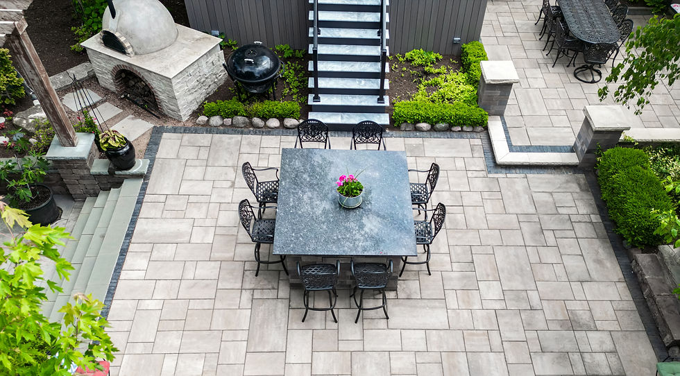 Aerial view of stone patio with dining table and pizza oven
