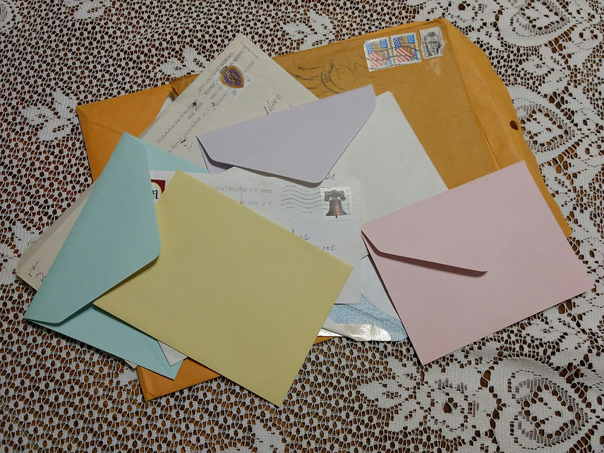 Colorful envelopes on a lace tablecloth, with an orange envelope in the background.