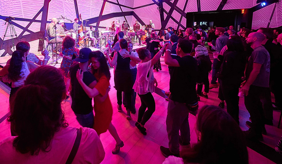 Audience seen from the stage at National Sawdust, watching and dancing to a live instrumental forró performance by Forró Sem Palavras, with a jazz orchestra on stage, during Forró New York Weekend (Autumn Edition 2023).