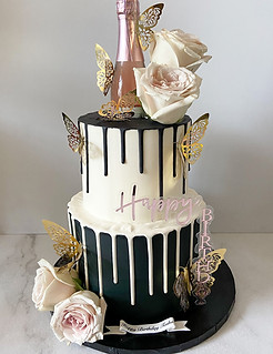Two Tiered black and while color blocked cake with drips, baby pink roses, and an acrylic number cake topper