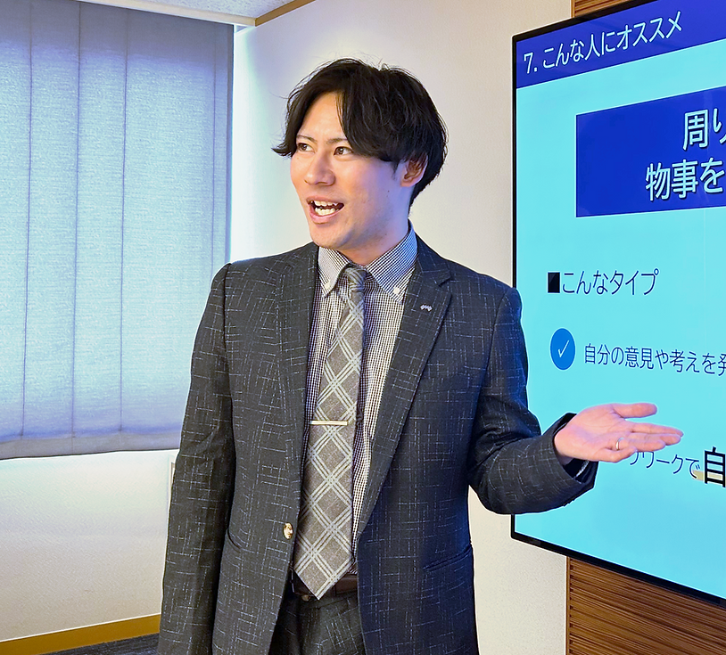 モニターの横で発表を行う男性社員