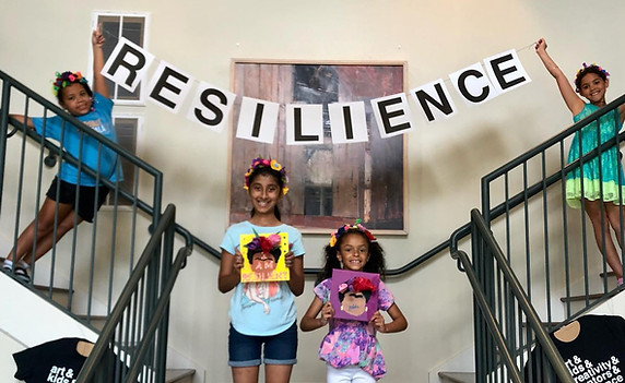 Two girls showing off their art under a banner that says Resilience