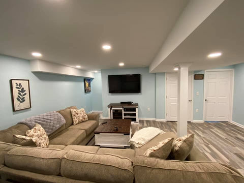 Finished basement with vinyl plank flooring, recessed lighting, blue walls, and sectional seating in a family room remodel in Chadds ford, PA