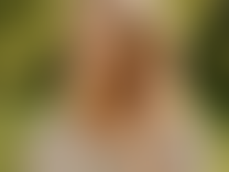 Middle-aged woman smiling peacefully with eyes closed, gently touching her ear while standing outdoors in a sunlit garden, symbolizing healthy hearing and vibrant aging.