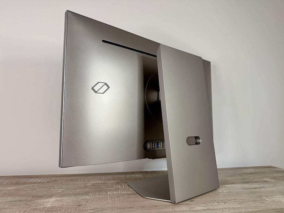 The Odyssey 3D Gaming Monitor's silver back shell with logo, USB ports, and a stand on a wooden desk. Minimalist design with neutral tones.