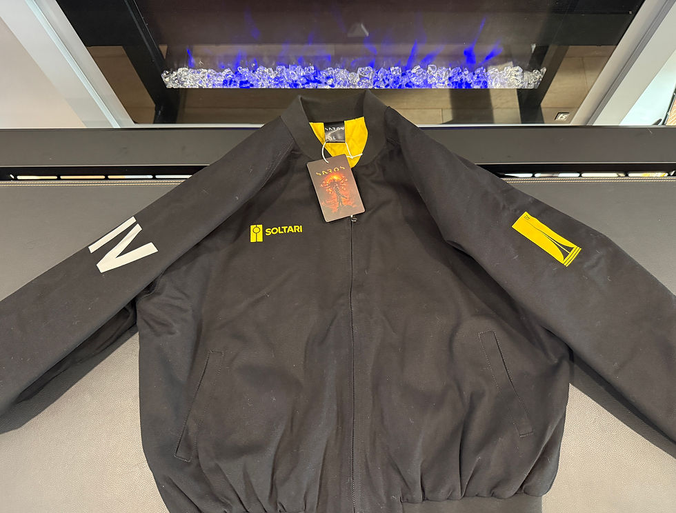 Black jacket with "SOLTARI" logo, yellow accents, and white "IV" on the sleeve. It's displayed on a table, with a fireplace in the background.