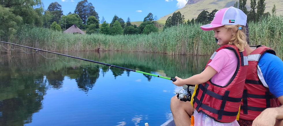 Little girl with fishing rod sitting in canoe in Drakensberg