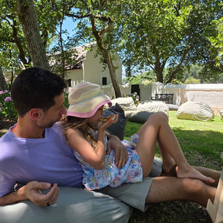 Father and daughter eating pizza on beanbags on the grass