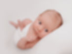 Newborn baby wrapped in white during a photography session.