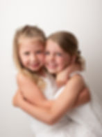 Two young sisters hugging for newborn and family photography.