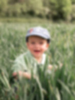 Young boy smiling in a field by an outdoor family photographer