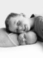 Young boy smiling next to sleeping newborn in studio family photography.