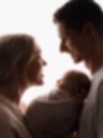 Parents smiling at swaddled baby in a newborn and family photography session