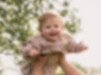Smiling baby in a plaid dress, newborn and family portfolio.