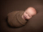 Sleeping baby in a brown wrap from a newborn portfolio