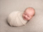 Smiling newborn baby swaddled for newborn photography