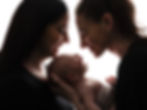Two mothers smiling at their baby during newborn photography
