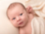 Newborn photography of an alert baby wrapped in a blanket.