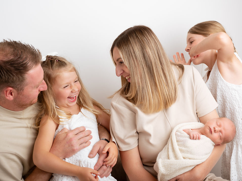 Laughing parents with kids and newborn in studio family photography