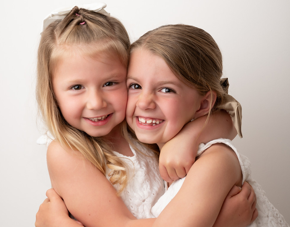 Two young sisters hugging during studio family photography.