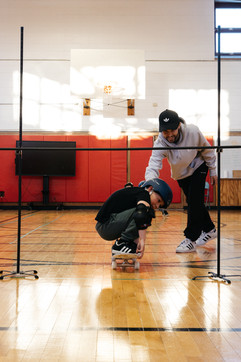 connect skateboarding program at J.V.F Elementary School.  kids skating under a skate limbo stick.
