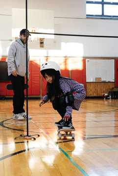 connect skateboarding program at J.V.F Elementary School.  kids skating under a skate limbo stick.
