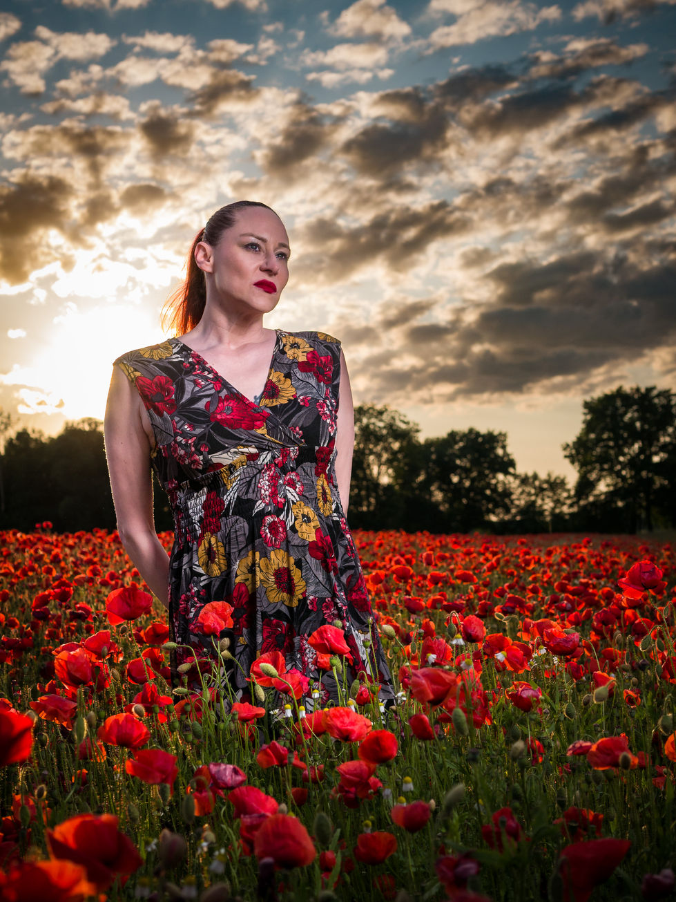 Porträtshooting zum Sonnenuntergang einer Frau im Mohnblumenfeld