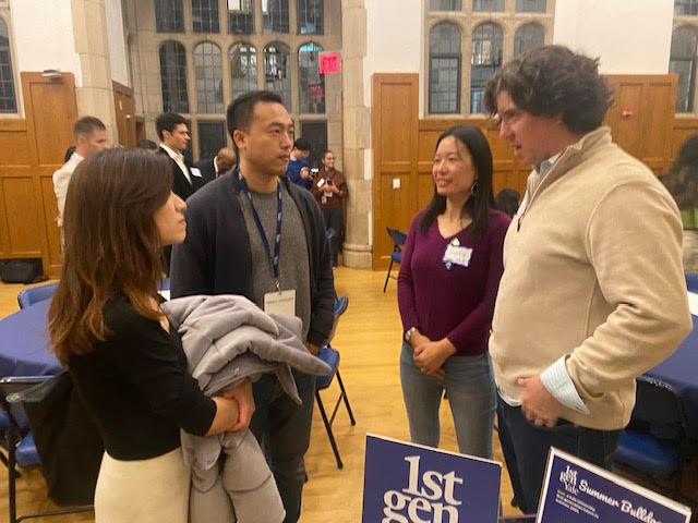 Four people stand and talk with a 1stGenYale sign in the foreground
