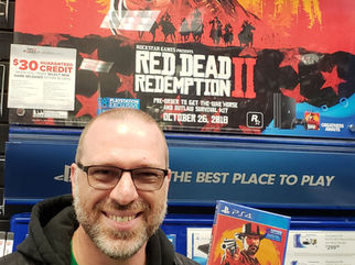 Voice actor and Red Dead Redemption 2 cast member Tom Dheere holding a copy of the game at a GameStop in 2018.