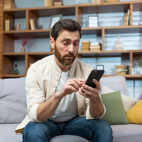 Un homme sur son canapé en train de discuter sur smartphone