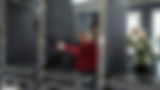 Woman aims a rifle at a shooting range with people watching her shoot.