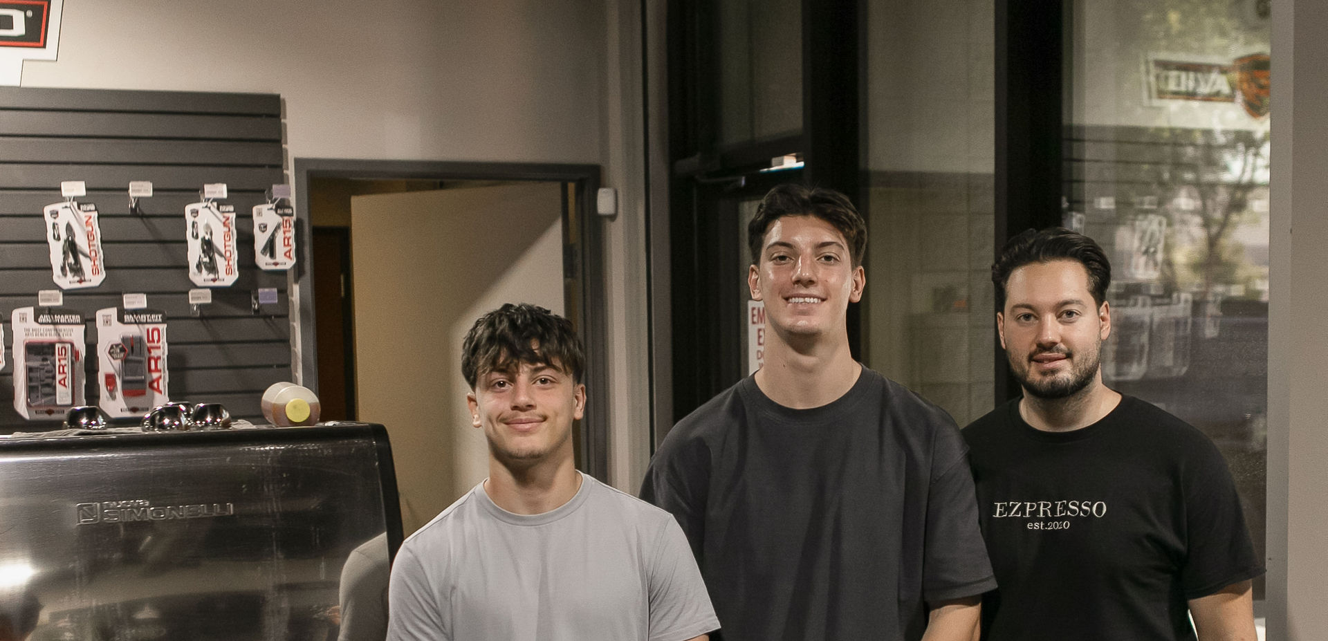Three men posing in front of counter.