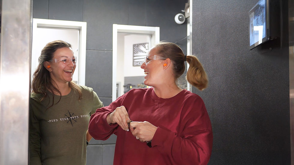 2 women at the shooting range smiling and laughing.
