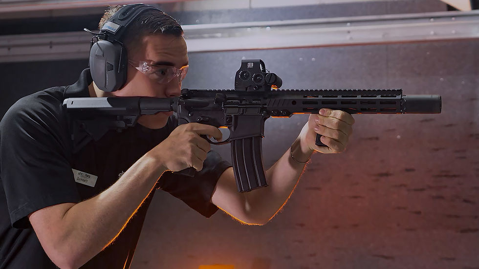 Man aiming black rifle at a shooting range with hearing protection on