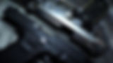 Two handguns, a black Glock and silver handgun, on a dark surface.