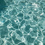 Sunlight reflecting on clear turquoise swimming pool water