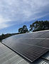 Solar panels on a corrugated metal roof under a blue sky