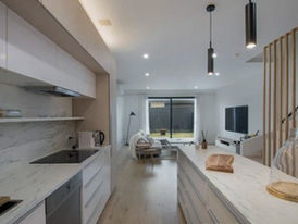 Modern open-plan kitchen and living room with feature LED and pendant lighting