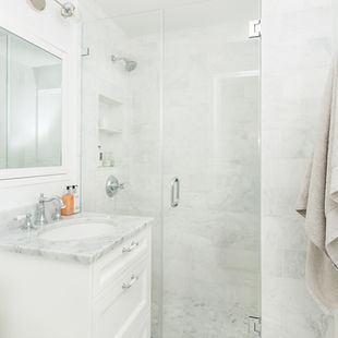 Bright white marble bathroom featuring a glass walk-in shower, custom vanity, and timeless bathroom interior design inspiration.