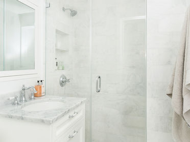 Bright white marble bathroom featuring a glass walk-in shower, custom vanity, and timeless bathroom interior design inspiration.